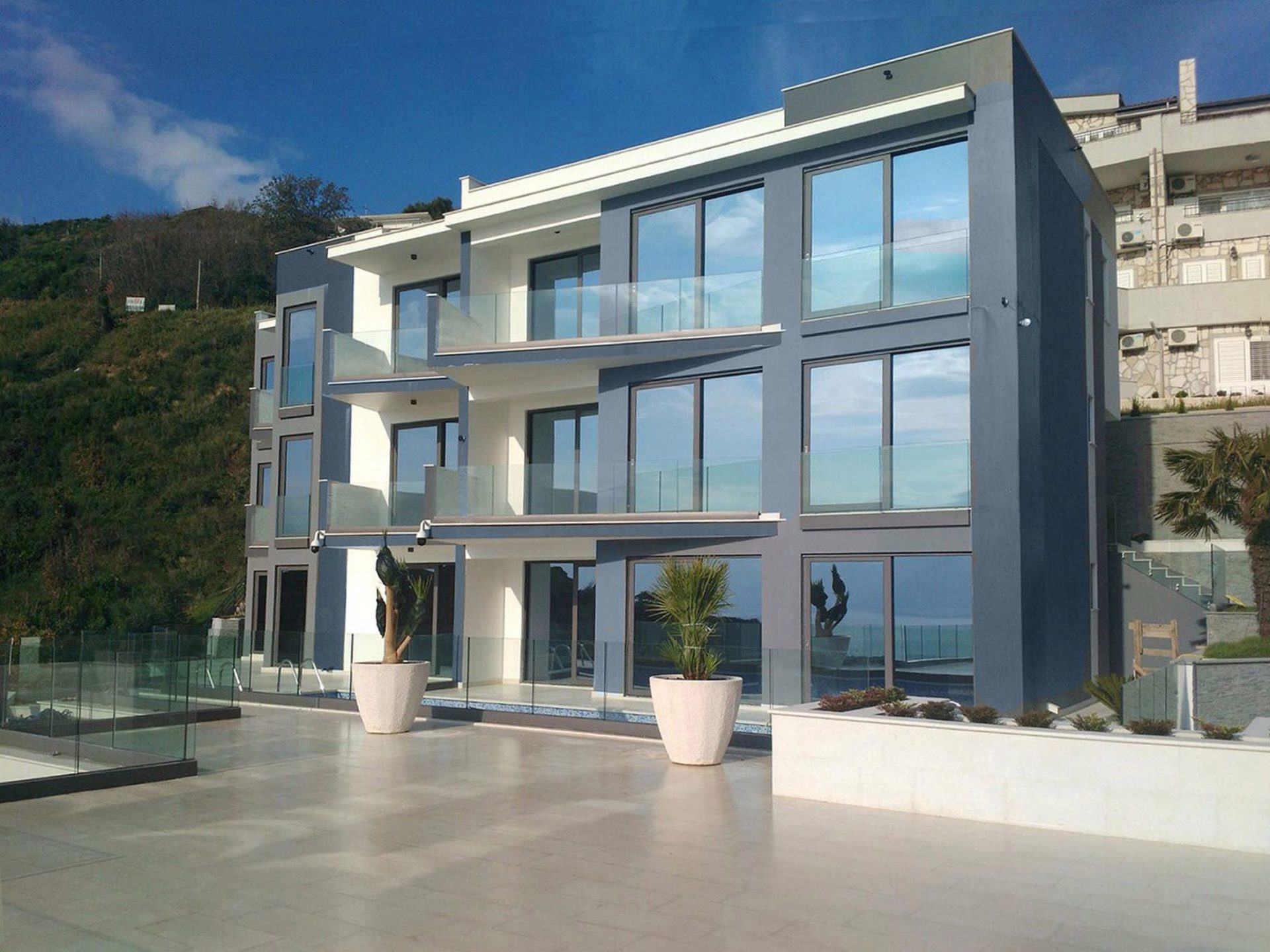 Moderne Villa in Budva, Montenegro: Fassade mit Panoramafenstern, Glasbalkonen und Poolterrasse.