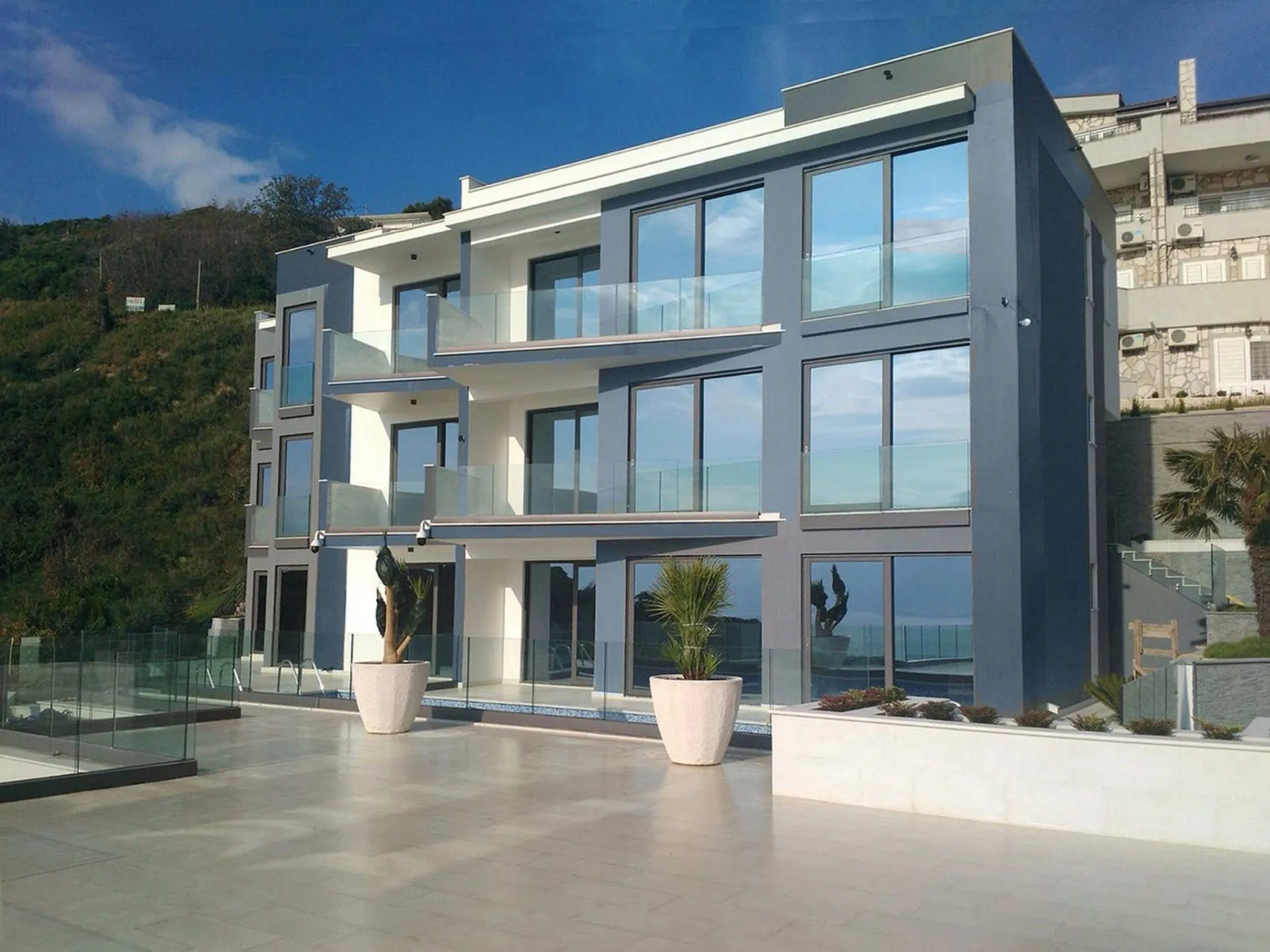 Moderne Villa in Budva, Montenegro: Fassade mit Panoramafenstern, Glasbalkonen und Poolterrasse.