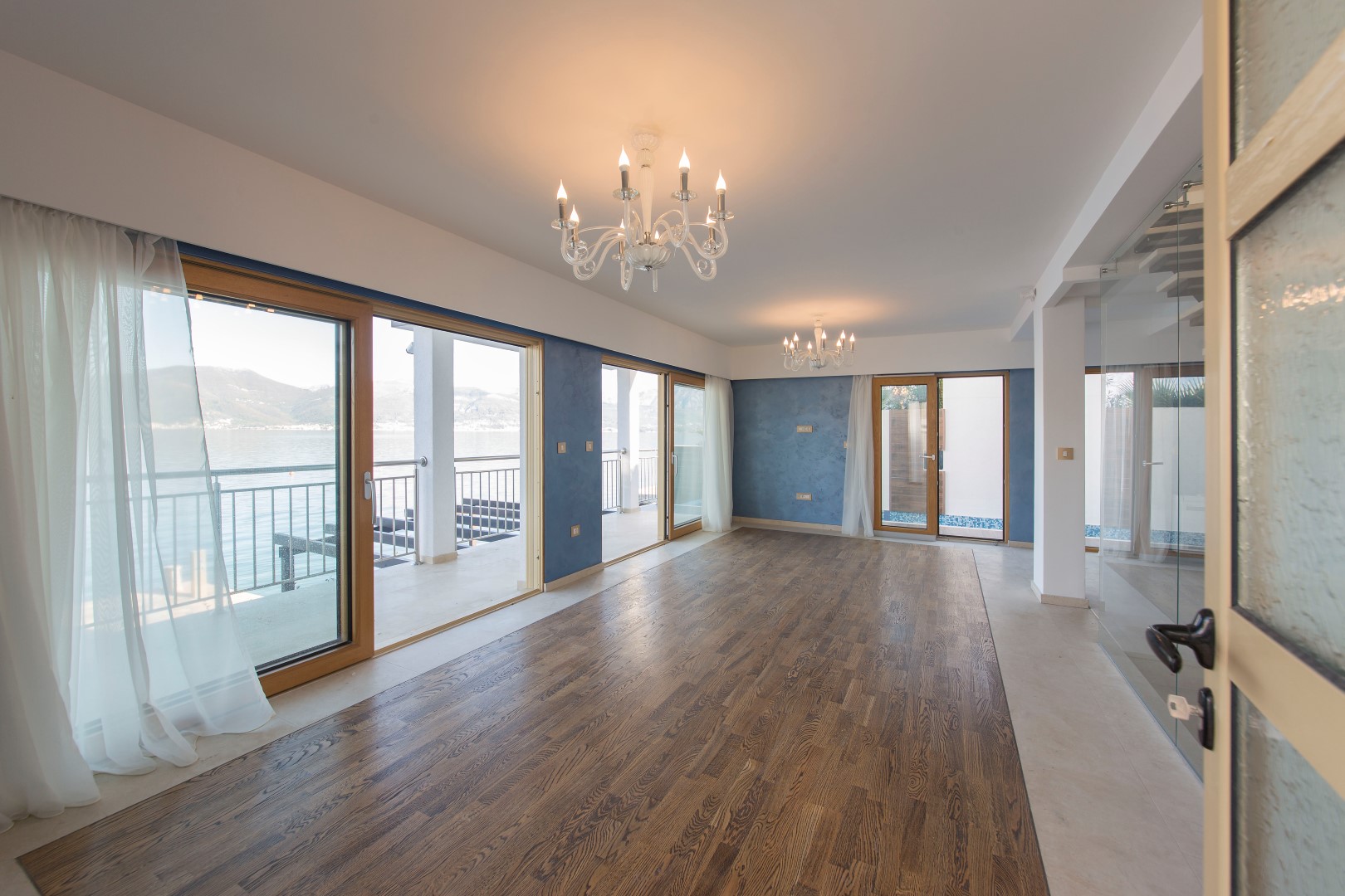 Spacious living room in a villa in Krašići, Montenegro, with panoramic windows, sea views, and access to the terrace.