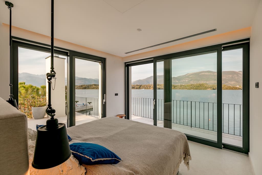 Schlafzimmer in einer Villa in Luštica, Montenegro: Panoramafenster mit Meerblick, modernes Interieur und Zugang zur Terrasse.