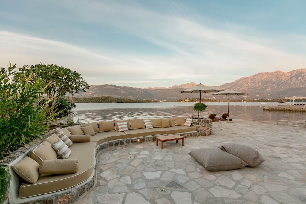 Terrasse der Villa in erster Meereslinie in Luštica, Montenegro: Steinbelag, Polstermöbel und Panoramablick auf das Meer.