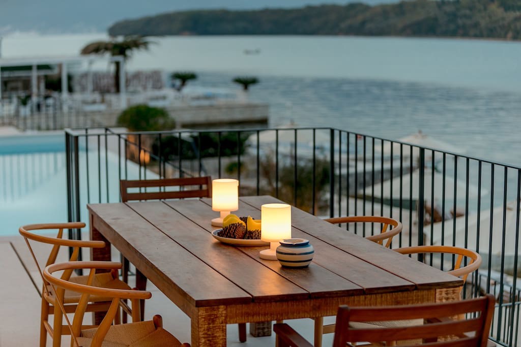 Terrasse der Villa in Luštica, Montenegro: Holztisch, Meerblick und Pool in erster Reihe an der Küste.