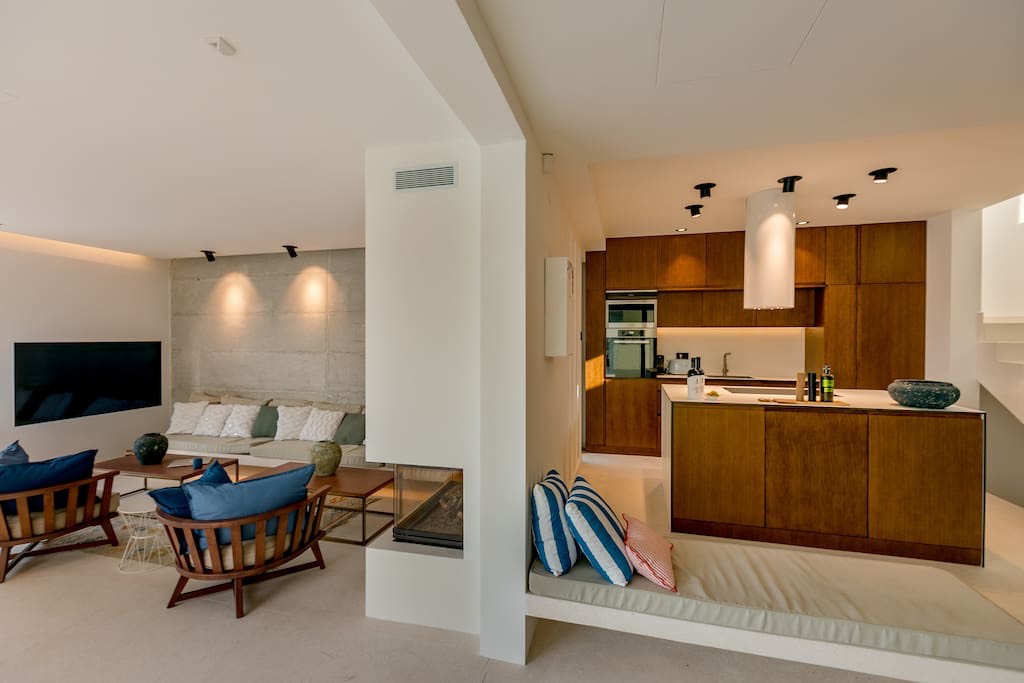 Modernes Wohnzimmer mit Küche und Kamin in einer Villa in Luštica, Montenegro: stilvolles Interieur, Holzmöbel.