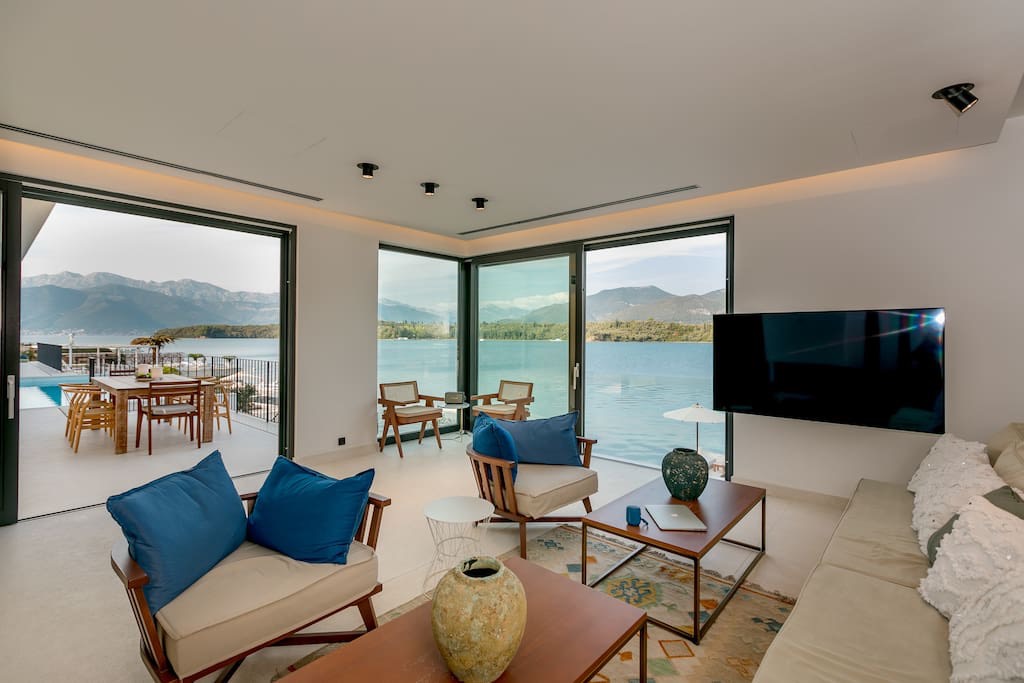 Wohnzimmer der Villa in Luštica, Montenegro: Panoramafenster mit Meerblick, moderne Möbel und eine Terrasse mit Pool.