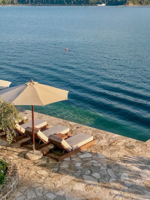 Private Terrasse der Villa in erster Meereslinie in Luštica, Montenegro: Liegestühle, Sonnenschirm und direkter Zugang zur Adria.