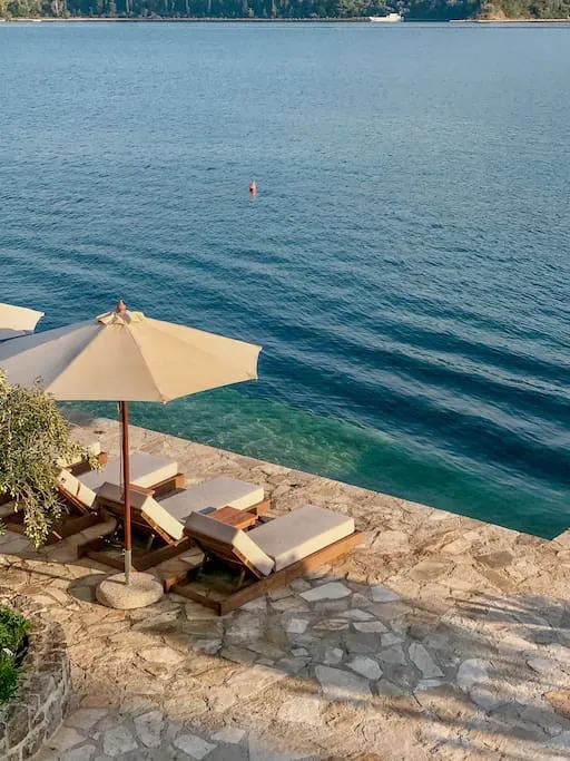 Private Terrasse der Villa in erster Meereslinie in Luštica, Montenegro: Liegestühle, Sonnenschirm und direkter Zugang zur Adria.