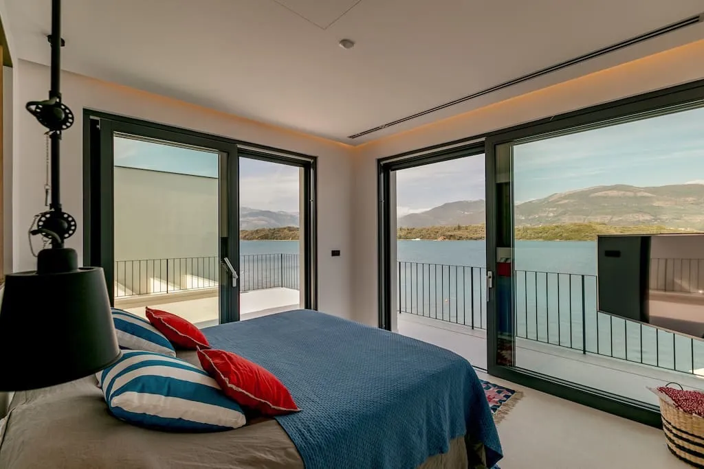 Schlafzimmer mit Panoramablick auf das Meer und die Berge in einer Villa in Luštica, Montenegro: modernes Interieur, Zugang zur Terrasse.