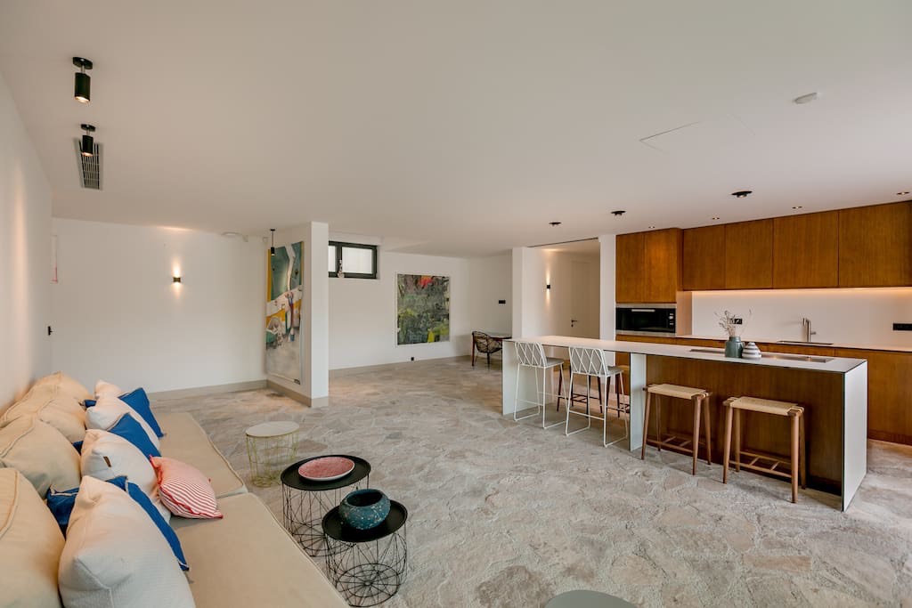 Modernes Wohnzimmer mit Küche in einer Villa in Luštica, Montenegro: Steinboden, Holzschränke und stilvolle Möbel.