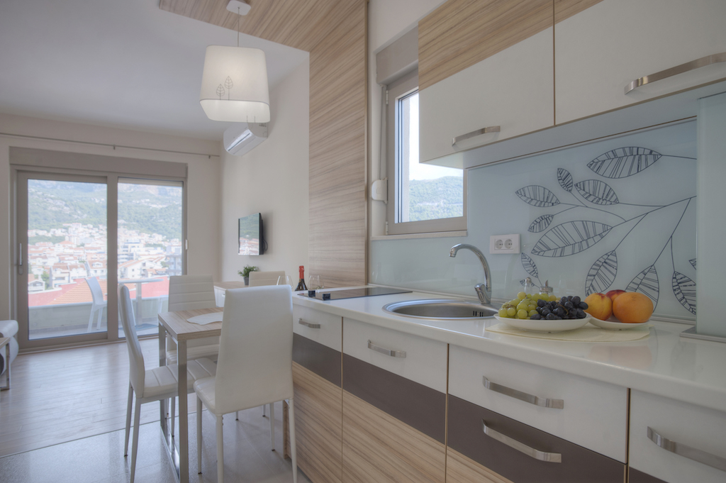 Moderne Küche in einer Wohnung in Budva, Montenegro: helle Einbauküche, Essbereich und Ausgang zur Terrasse mit Aussicht.