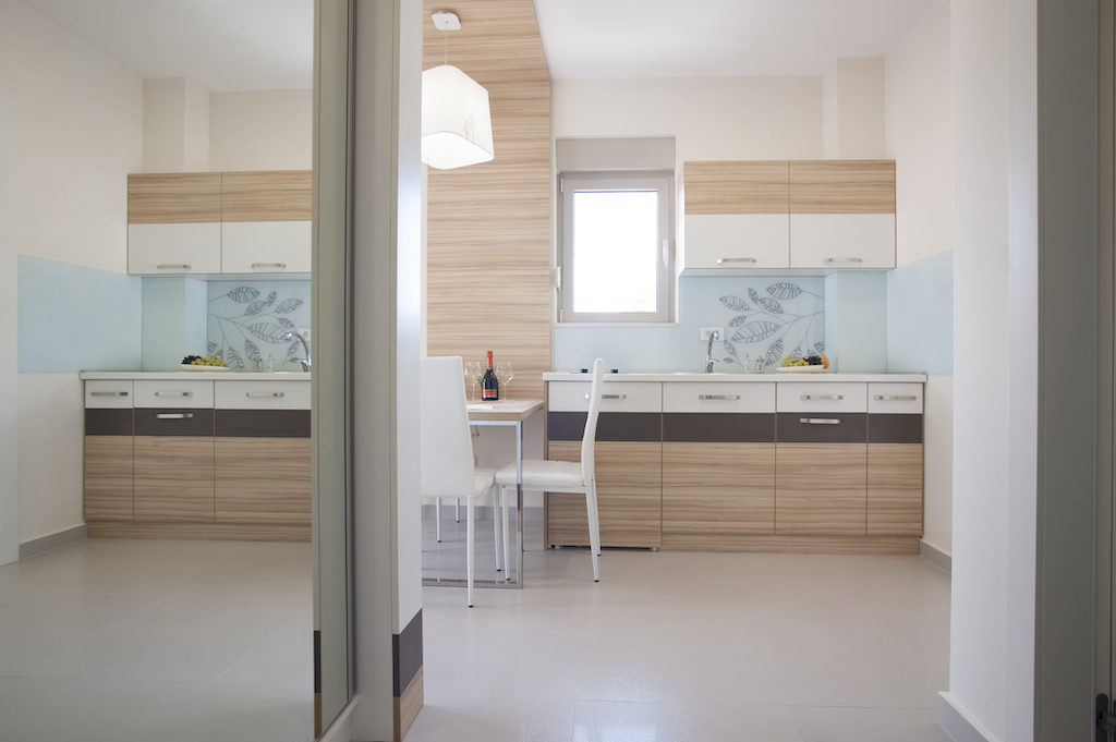Moderne Küche in einer Wohnung in Budva, Montenegro: helle Einbauküche, Essbereich und stilvolle Wandgestaltung.