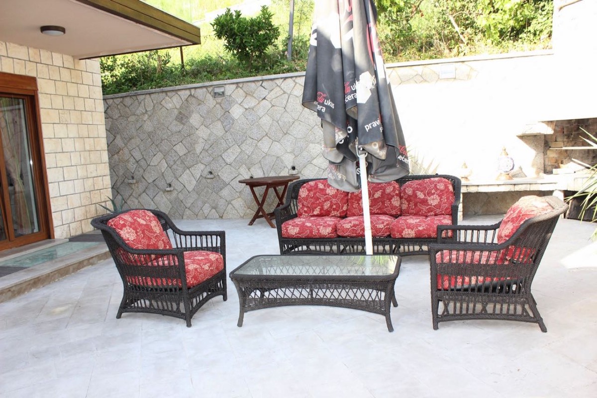 Gemütliche Terrasse mit Rattanmöbeln und Steinverkleidung in einer Villa in Budva, Montenegro.