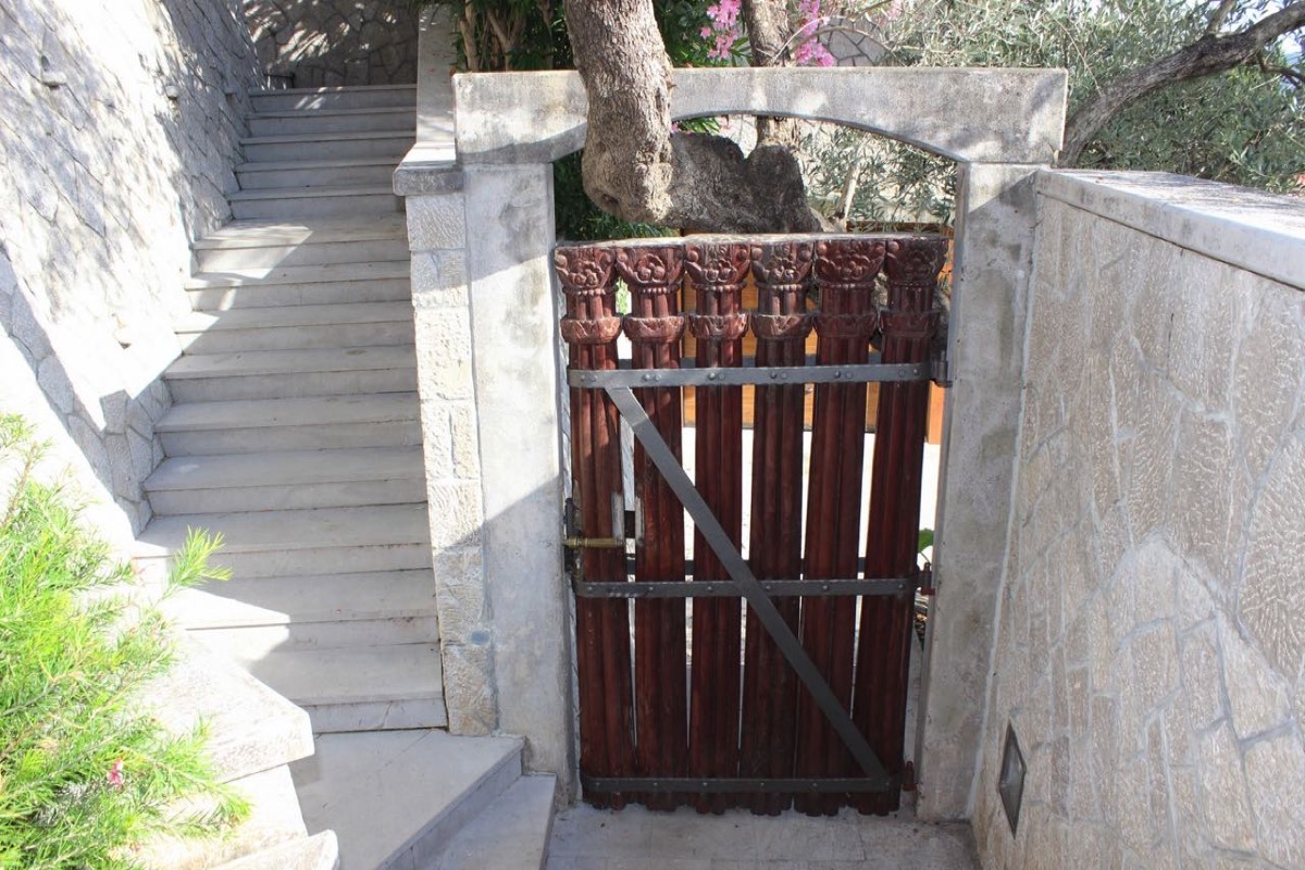 Dekoratives Holztor und Steintreppe an einer Villa in Budva, Montenegro.