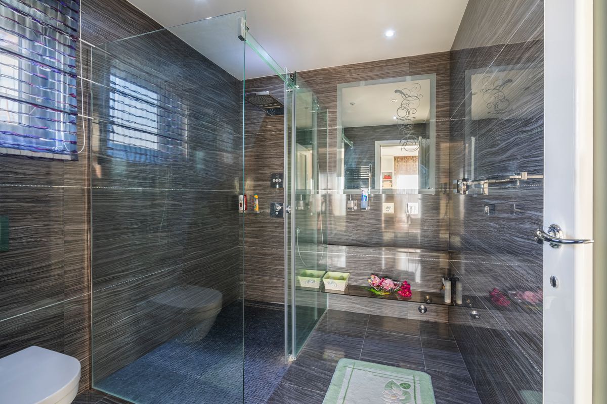 Modernes Badezimmer mit Duschkabine und Verkleidung aus dunklem Feinsteinzeug in einer Villa in Budva, Montenegro.