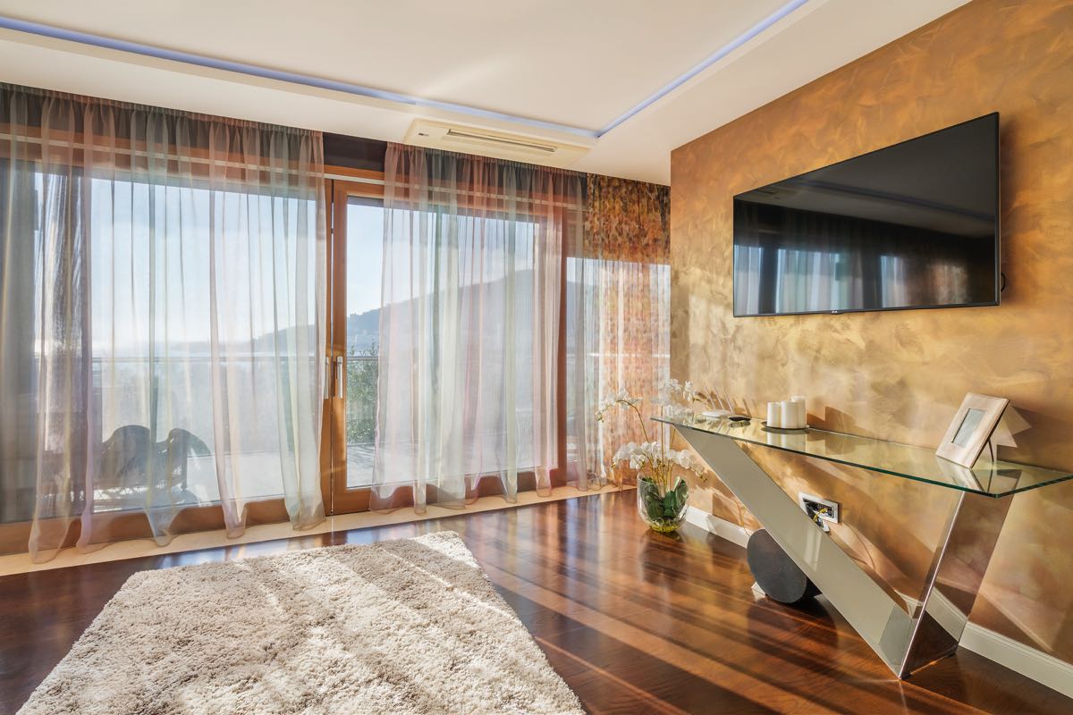 Wohnzimmer der Villa in Budva, Montenegro: Panoramafenster, Glaskonsole, TV an der Wand mit dekorativer Verkleidung.