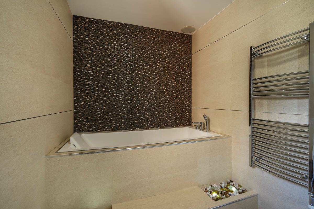 Modernes Badezimmer in einer Villa in Budva, Montenegro: eingebaute Badewanne, Mosaikfliesen und Handtuchheizkörper.