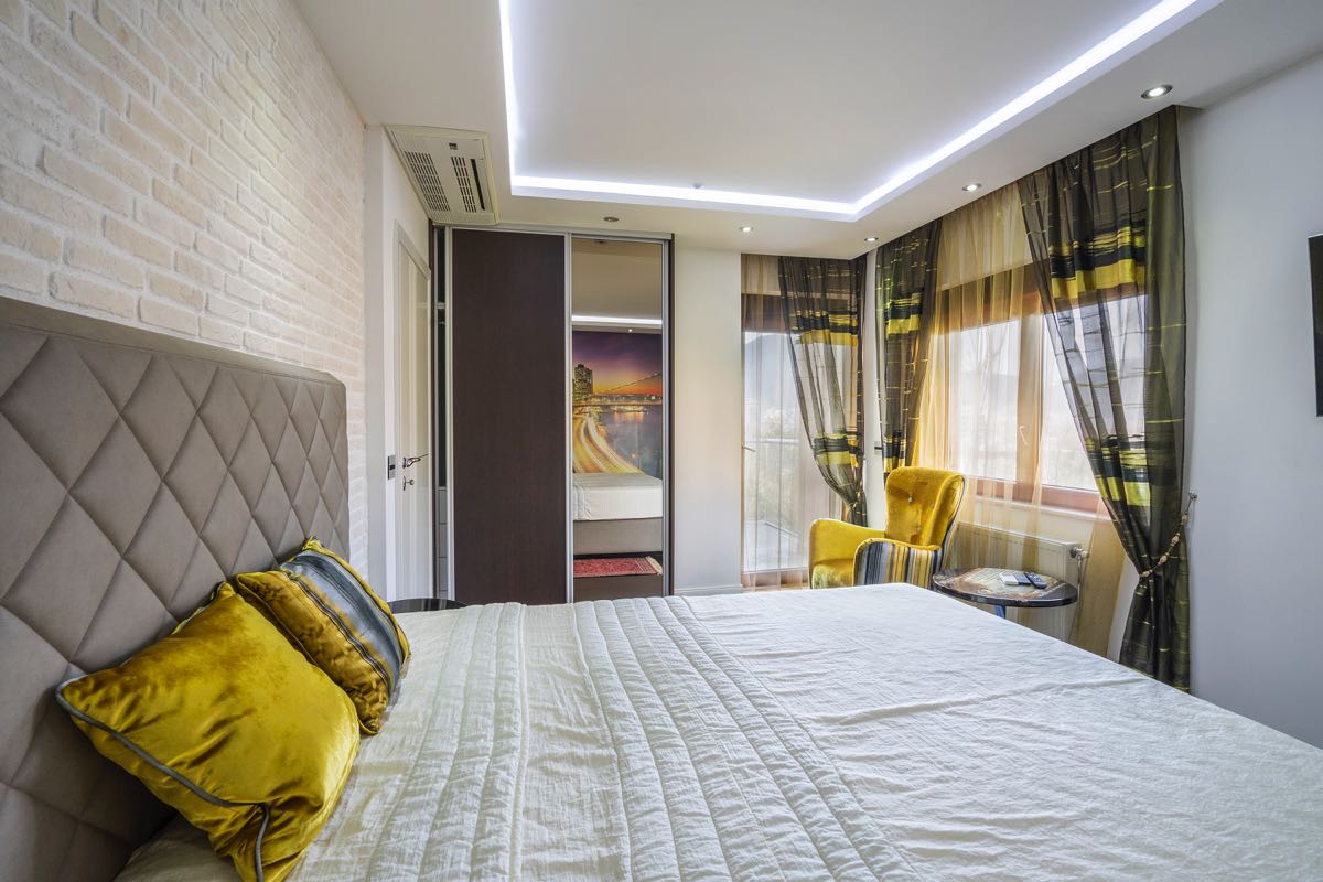 Modernes Schlafzimmer in einer Villa in Budva, Montenegro: Doppelbett, Ziegelwand, Kleiderschrank und gelber Sessel.