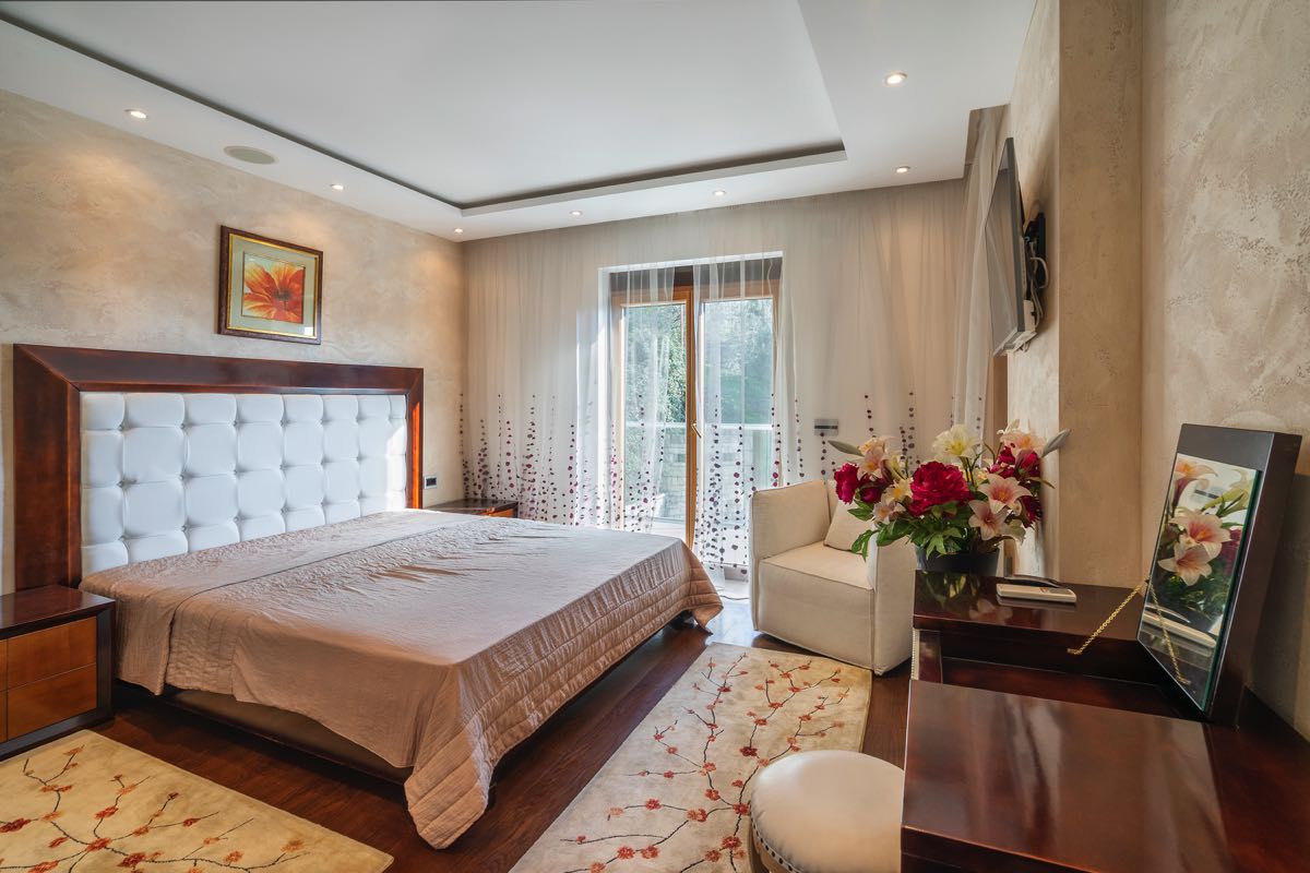 Gemütliches Schlafzimmer mit Doppelbett in einer Villa in Budva, Montenegro: stilvolles Interieur, helle Ausstattung und Balkon.