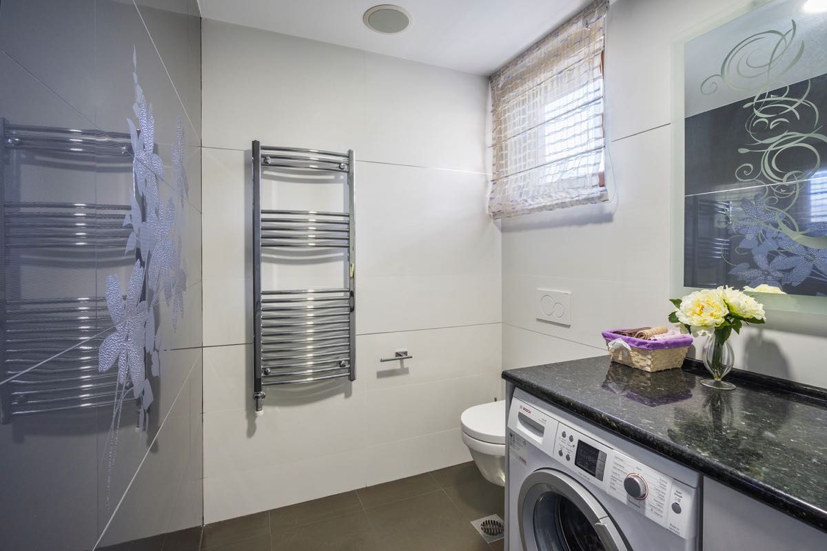 Modernes Badezimmer in einer Villa in Budva, Montenegro: stilvolle Ausstattung, Waschmaschine und Spiegel mit Dekor.