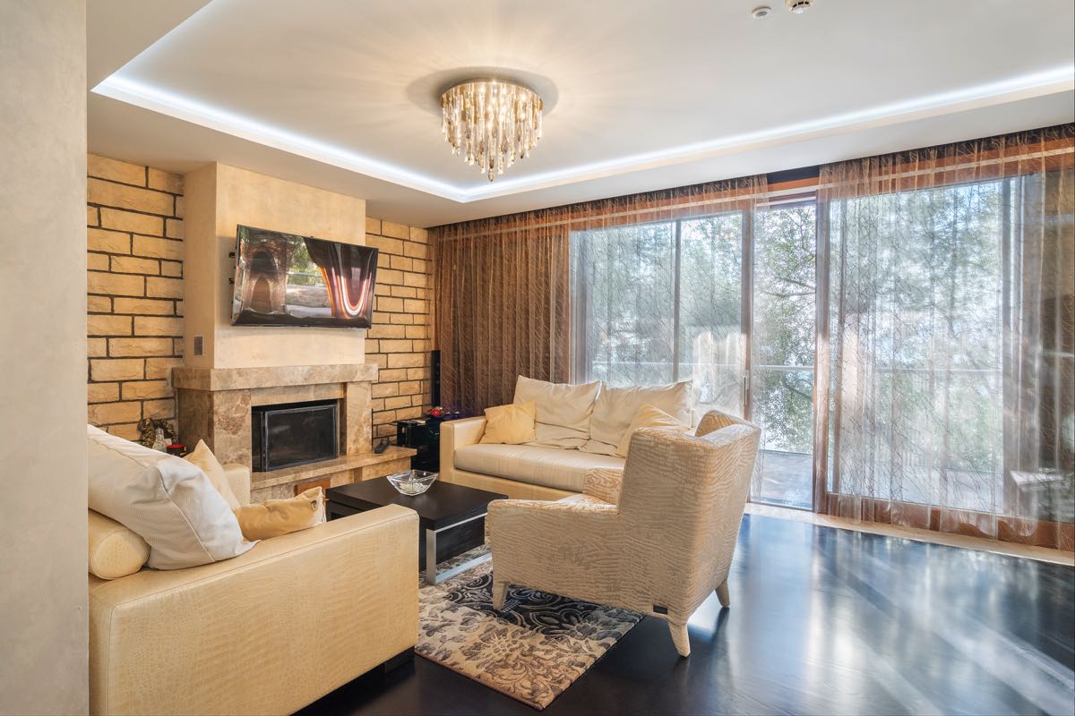 Wohnzimmer mit Kamin und Polstermöbeln in einer Villa in Budva, Montenegro: stilvolles Interieur mit Panoramablick aus dem Fenster.