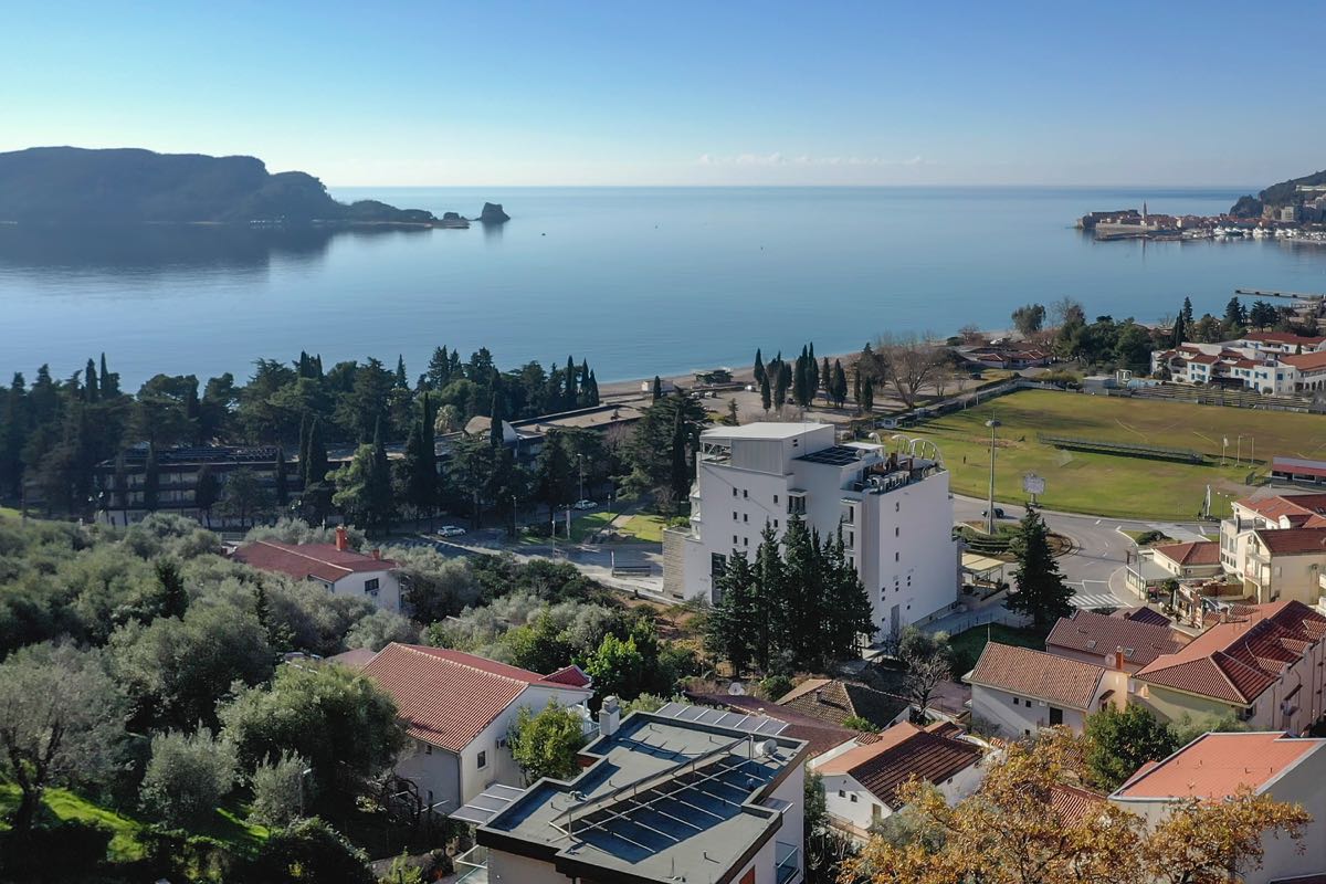 Panoramablick auf das Meer und die Küste von Budva, Montenegro: moderne Villa, Olivenhaine und Strand in der Ferne.