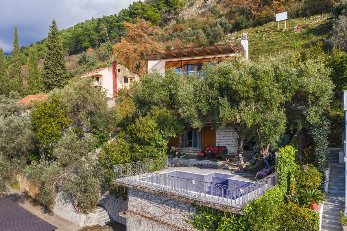 Zweistöckige Villa in Budva, Montenegro, mit Außenpool, Terrasse und Garten am Berghang zwischen Olivenbäumen.