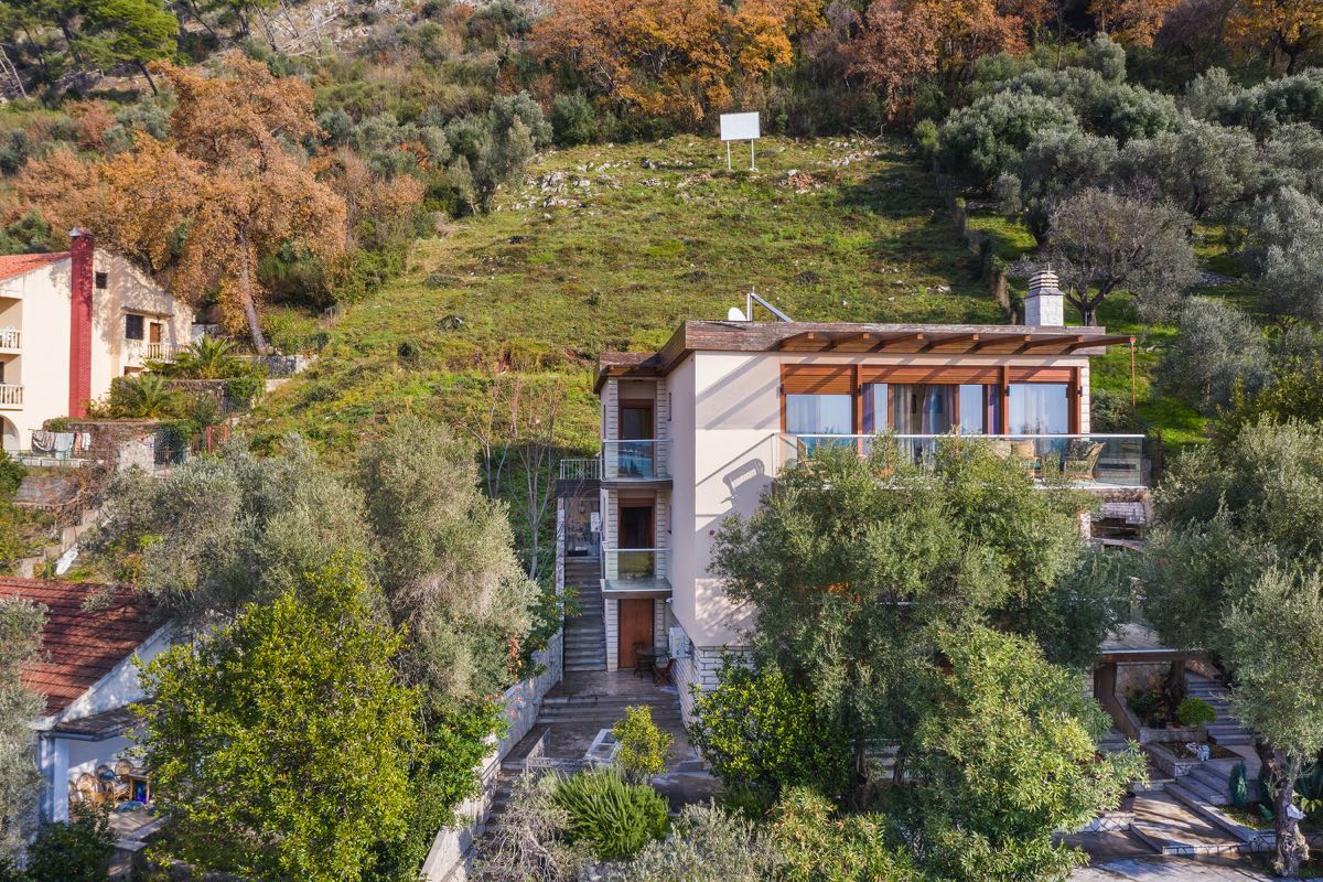 Dreistöckige Villa in Budva, Montenegro, mit Terrassen, Panoramafenstern und grünem Garten am Berghang.