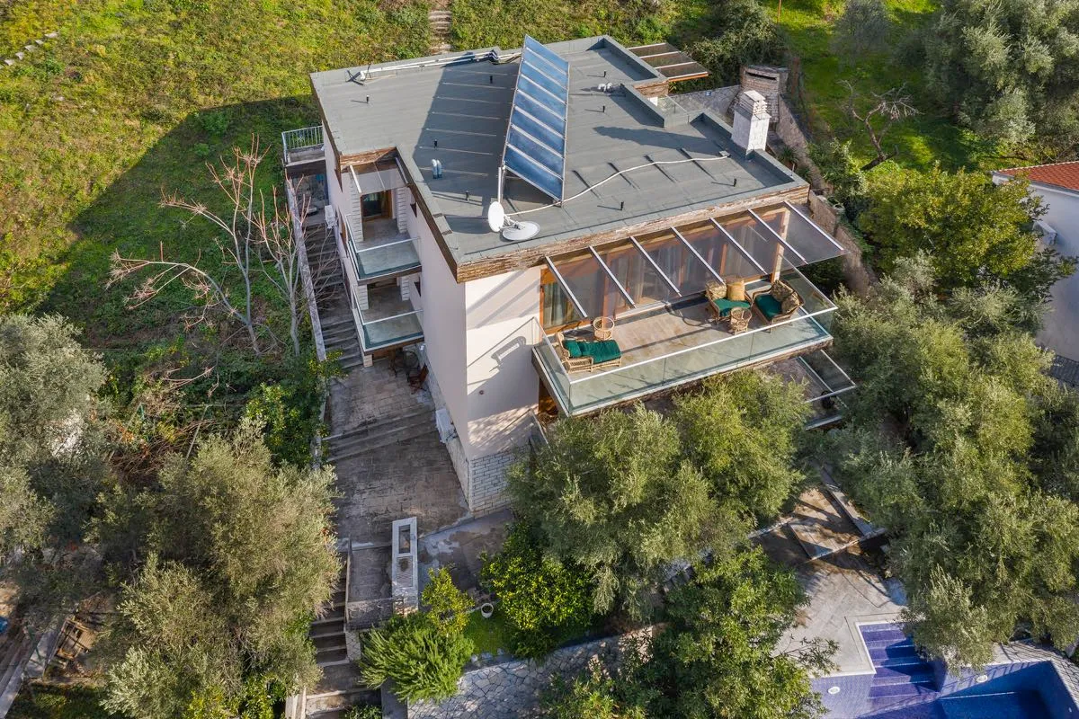 Vila u Budvi, Crna Gora: pogled odozgo na kuću sa terasama, baštenskim nameštajem, solarnim panelima i bazenom u dvorištu.