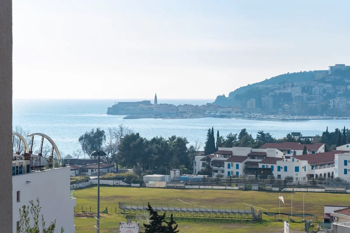 Pogled sa balkona vile u Budvi, Crna Gora: panorama Jadranskog mora, starog grada i fudbalskog terena.