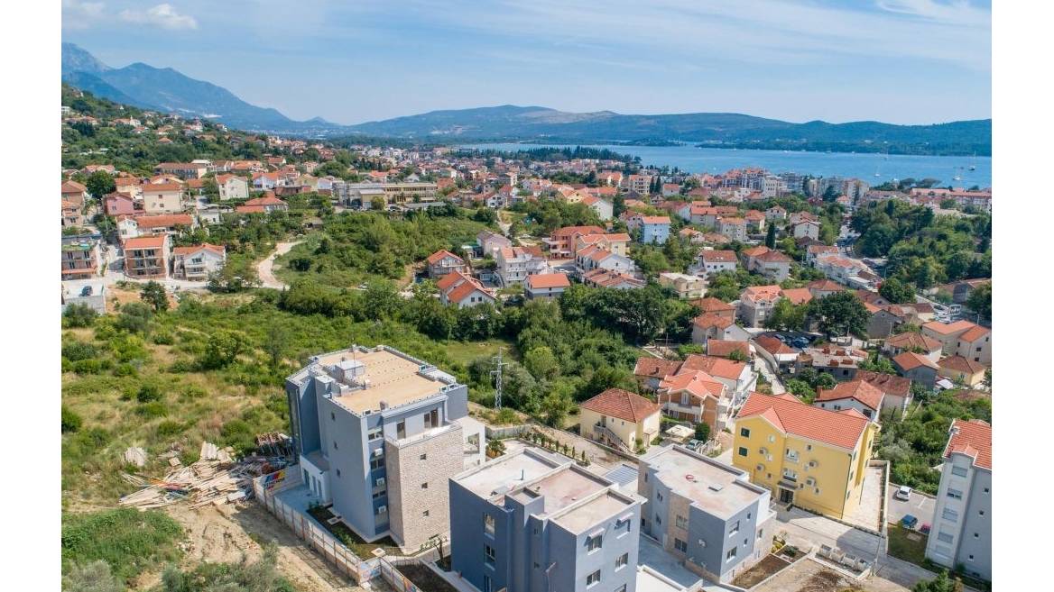 Panoramablick auf eine Wohnanlage in Tivat, Montenegro: moderne Häuser mit Terrassen und Meereslandschaft vor Bergkulisse.
