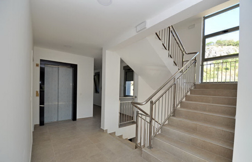 Moderner Eingangsbereich mit Aufzug und Treppe in einer Wohnanlage in Tivat, Montenegro: helles Interieur und Panoramafenster.