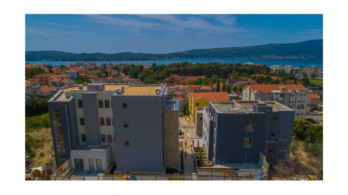 Luftaufnahme eines modernen Wohnkomplexes in Tivat, Montenegro, mit Panoramablick auf das Meer und die städtische Bebauung.