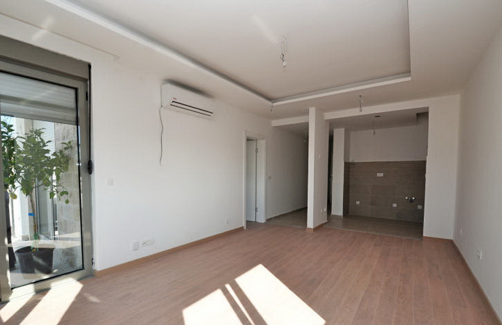 Helles Wohnzimmer mit Laminat und Klimaanlage in einer neuen Wohnanlage in Tivat, Montenegro, Blick auf die Terrasse.