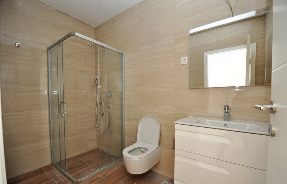 Modernes Badezimmer mit Duschkabine und weißem Waschtisch in einer Wohnanlage, Tivat, Montenegro.