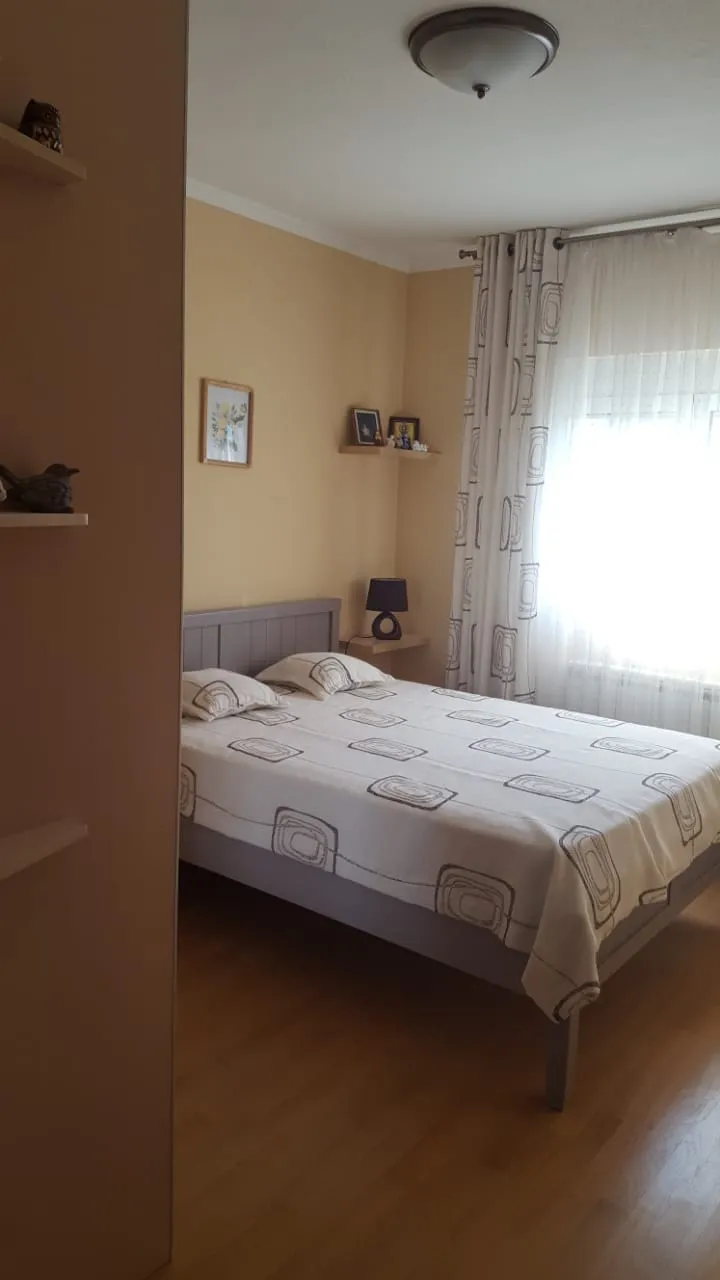 Cozy bedroom with a double bed in a house in Shushan, Montenegro: light finishes, parquet flooring, and patterned curtains.
