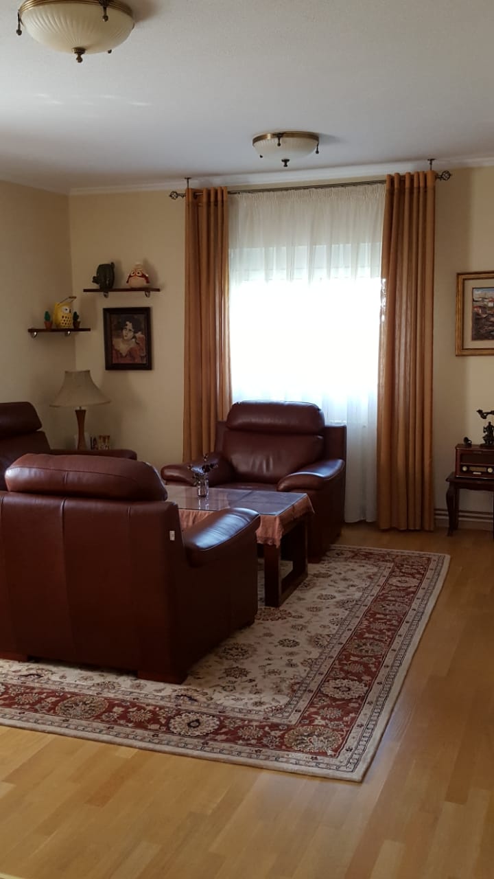Уютная гостиная в доме в Шушани, Черногория: кожаные кресла, ковер, паркетный пол и классический интерьер.