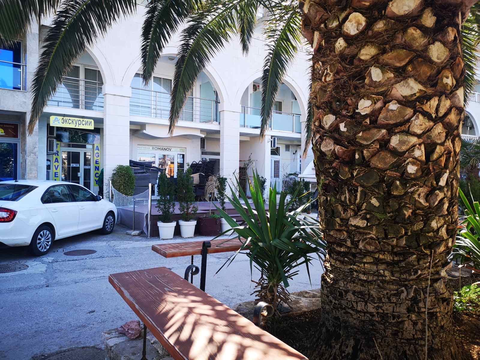 Façade d’un local commercial à Rafailovići, Monténégro : entrée avec arches, palmier et parking devant le restaurant.