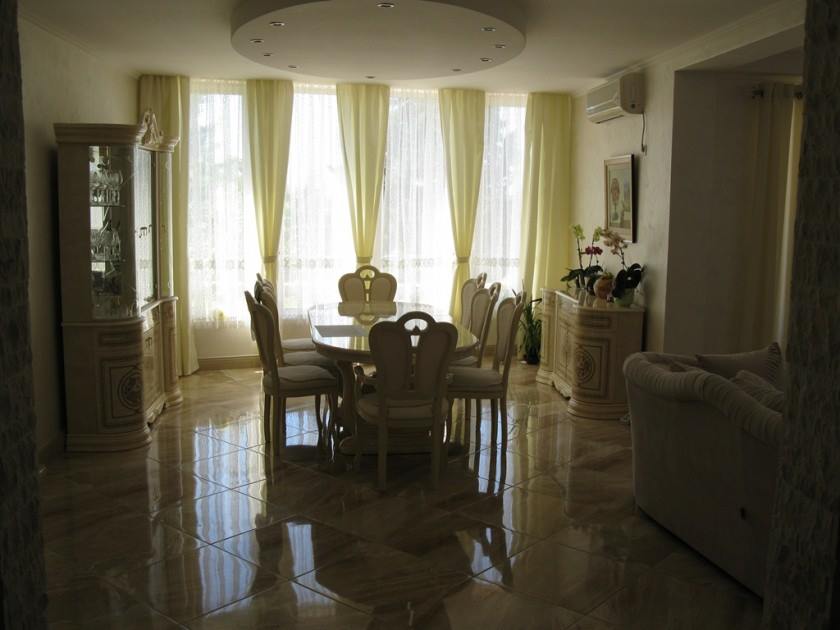 Salon avec coin repas dans une villa à Šušanj, Monténégro : mobilier classique, sol en marbre et baies vitrées panoramiques.