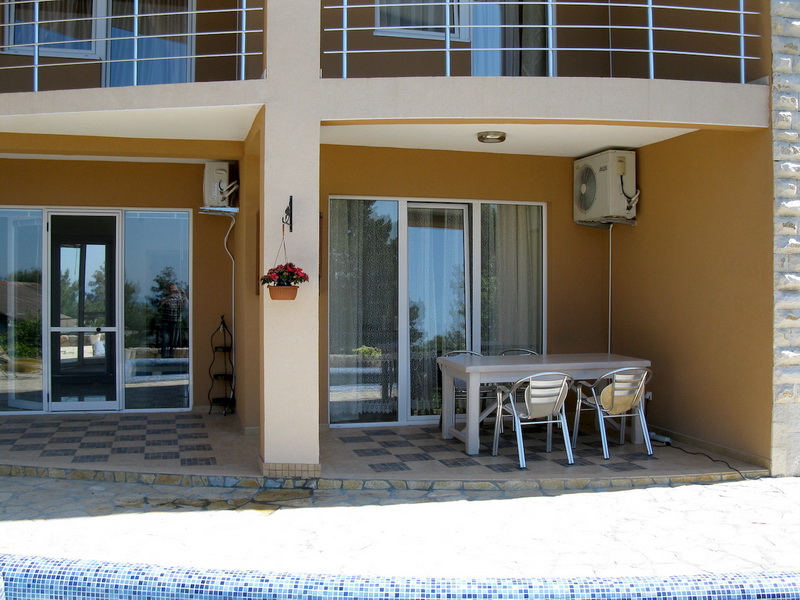 Terrasse de la villa à Shushan, Monténégro : coin repas avec table et chaises, baies vitrées panoramiques et vue sur la piscine.