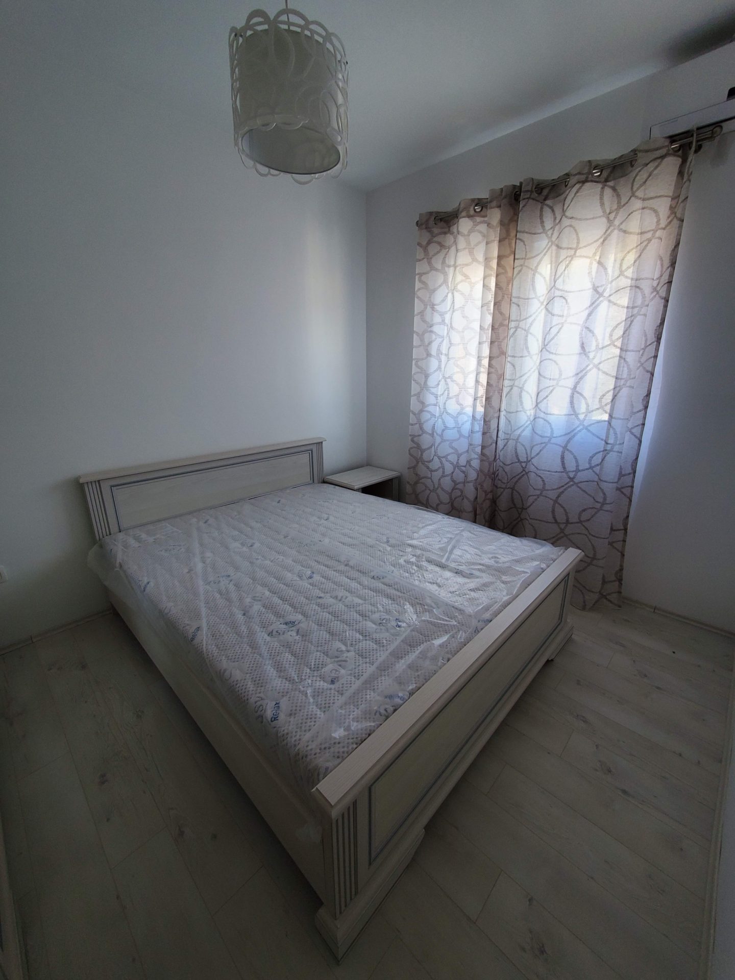 Helles Schlafzimmer mit Doppelbett in einer Wohnung in Budva, Montenegro: Laminat, neue Möbel und Vorhänge an den Fenstern.