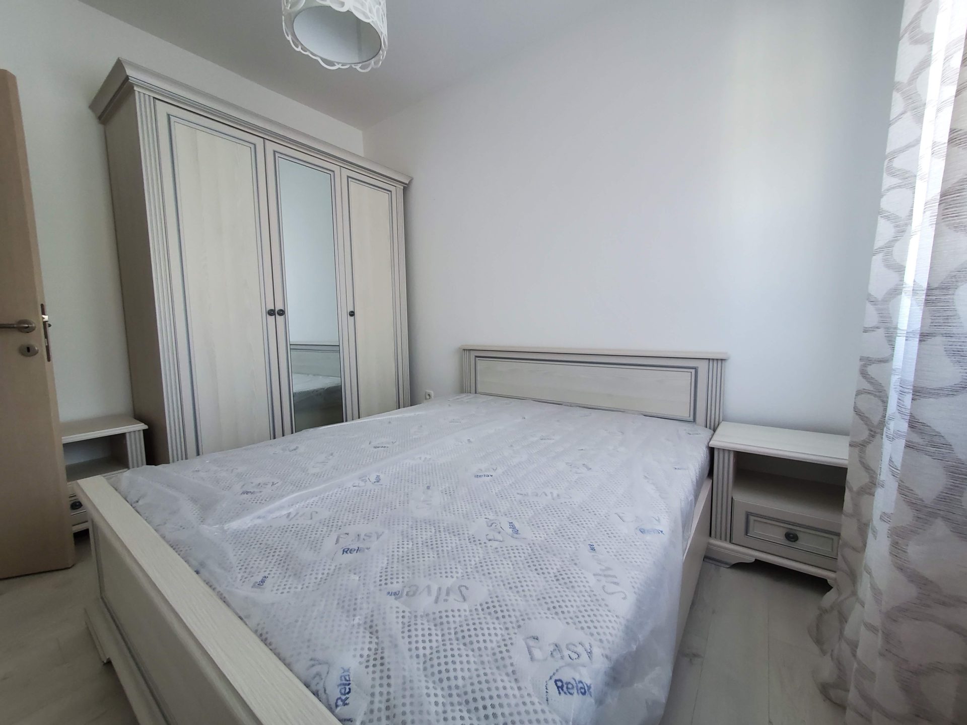 Helles Schlafzimmer in einer Wohnung in Budva, Montenegro: Doppelbett, Kleiderschrank mit Spiegel und Nachttische in hellen Tönen