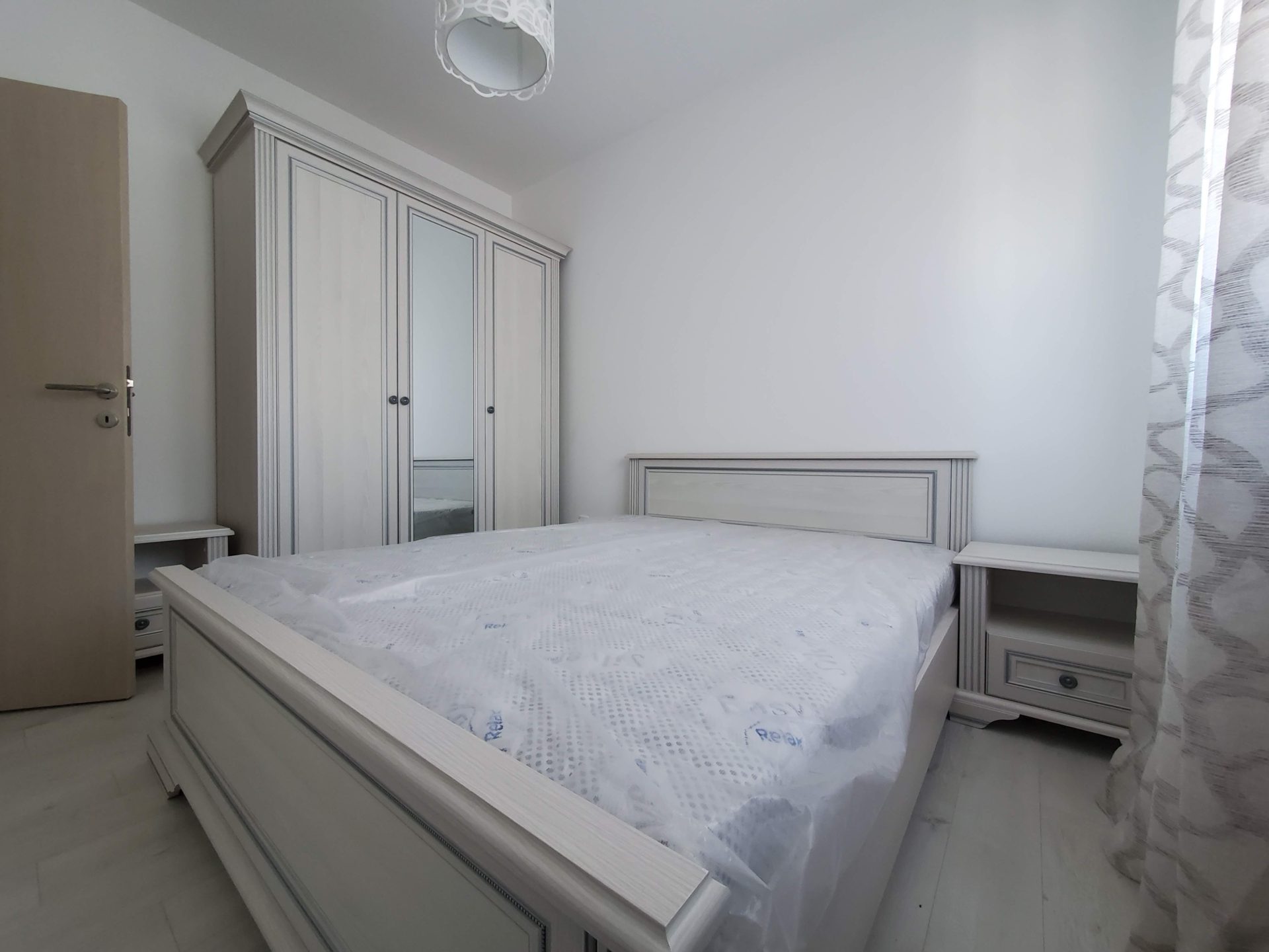 Helles Schlafzimmer in einer Wohnung in Budva, Montenegro: Doppelbett, Kleiderschrank mit Spiegel und Nachttische.