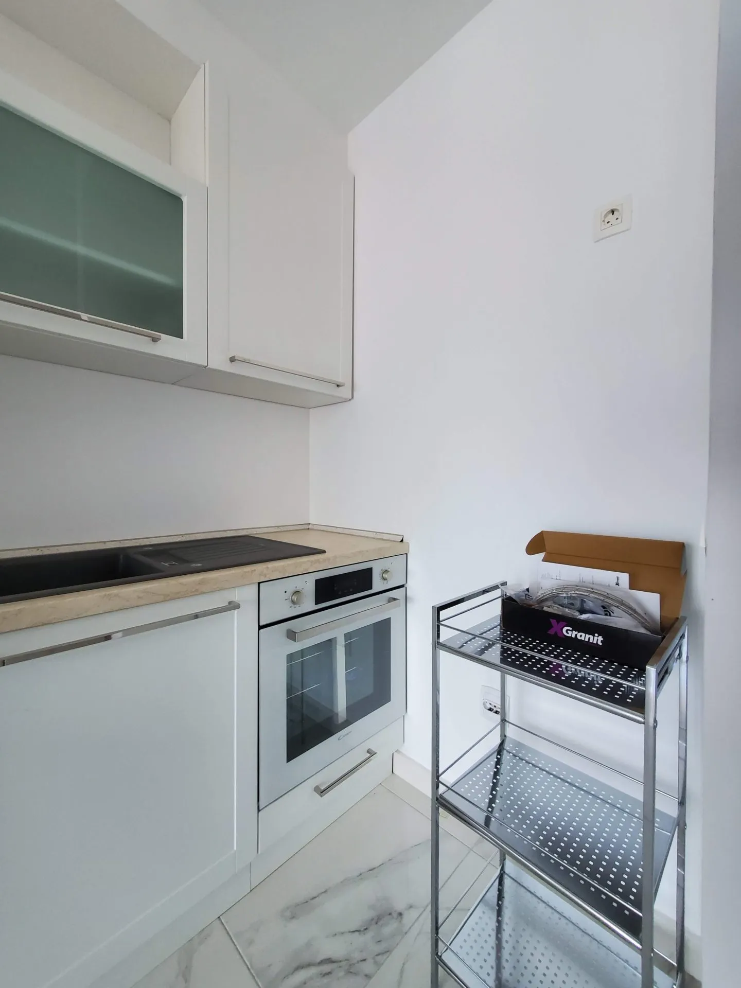 Moderne weiße Küche mit Geräten in einer Wohnung in Budva, Montenegro: Einbauofen und Steinspüle.