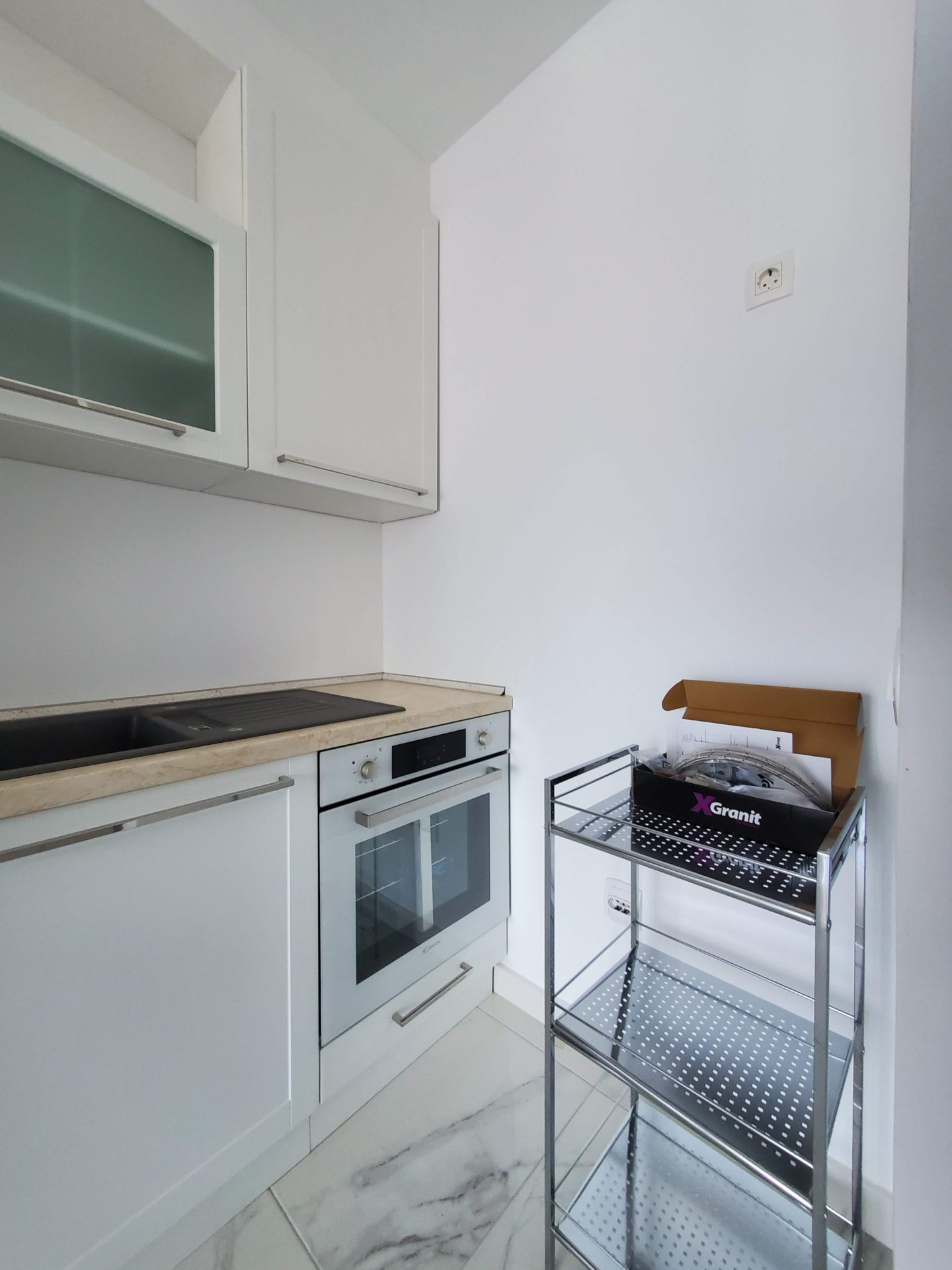 Moderne weiße Küche mit Einbaugeräten in einer Wohnung, Budva, Montenegro. Kompakte Küchenzeile mit Spüle.