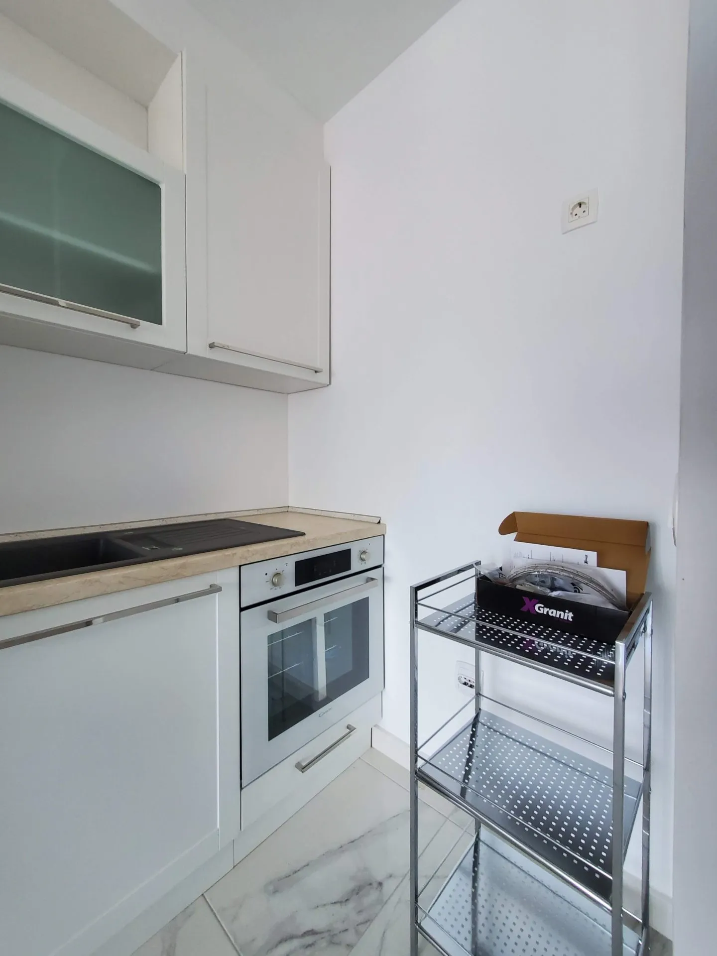 Moderne weiße Küche mit Einbaugeräten in einer Wohnung, Budva, Montenegro. Kompakte Küchenzeile mit Spüle.