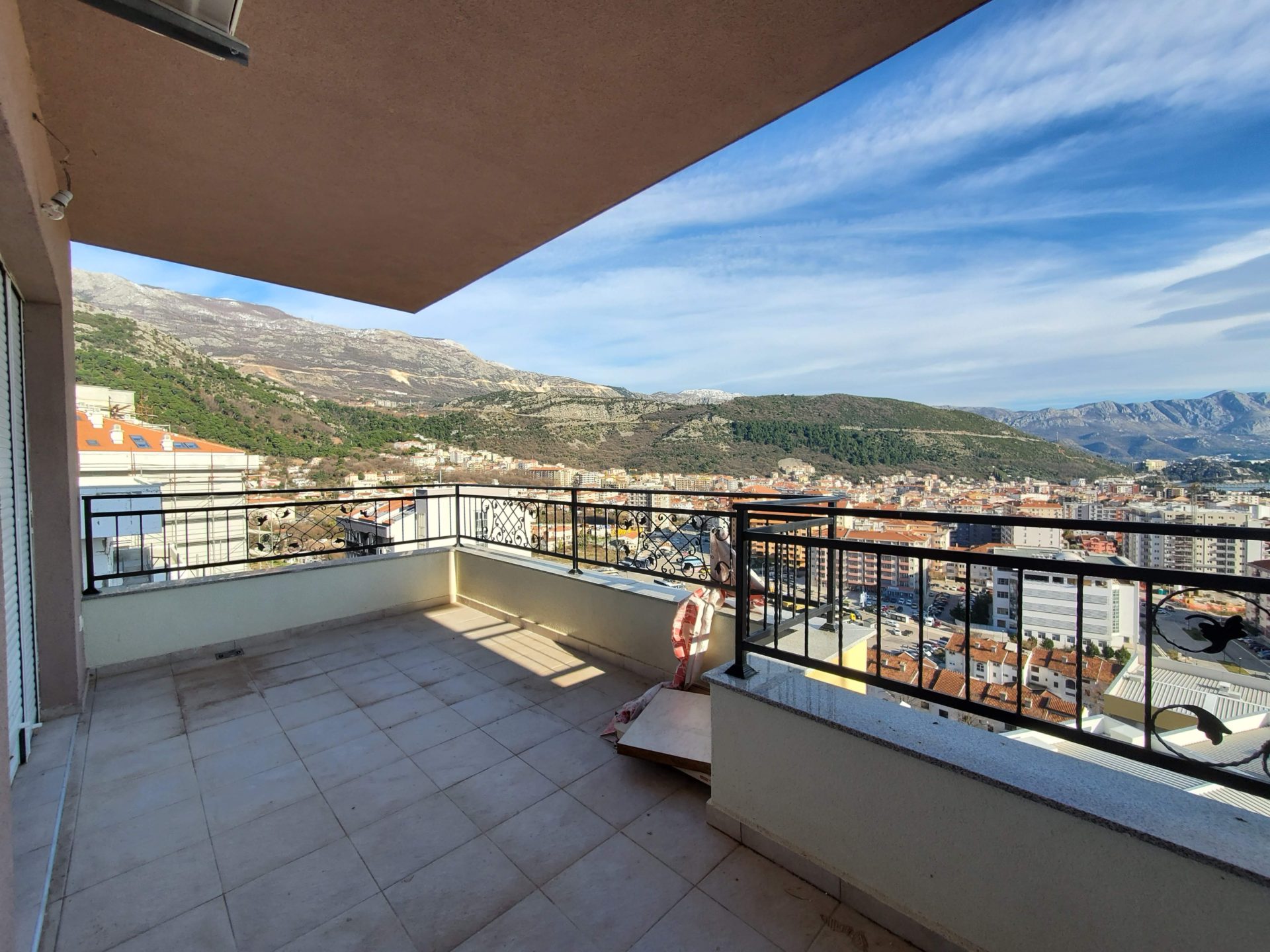 Geräumiger Balkon mit Panoramablick auf die Berge und die Stadt Budva, Montenegro, Fliesenboden, schmiedeeisernes Geländer.