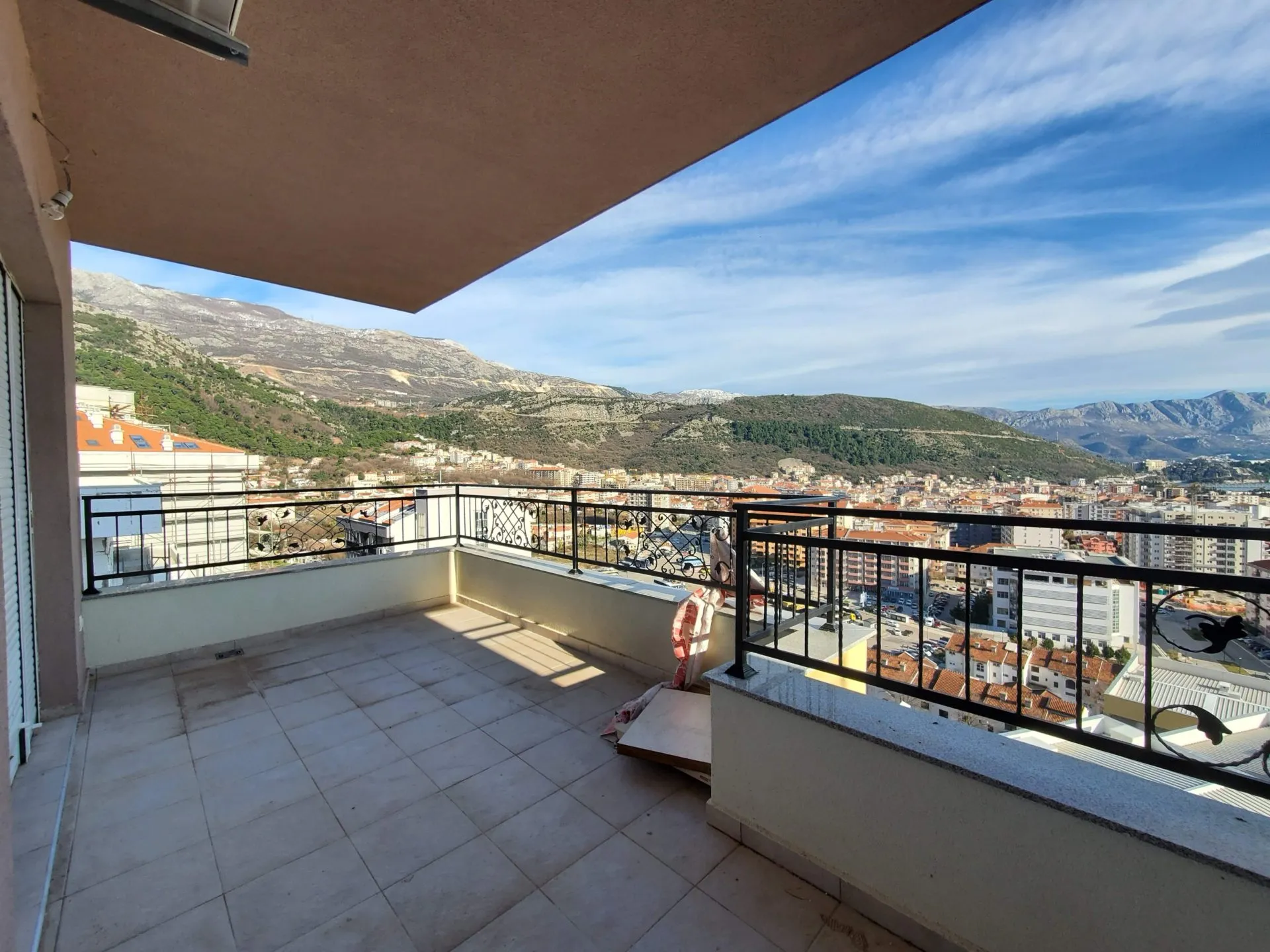 Geräumiger Balkon mit Panoramablick auf die Berge und die Stadt Budva, Montenegro, Fliesenboden, schmiedeeisernes Geländer.