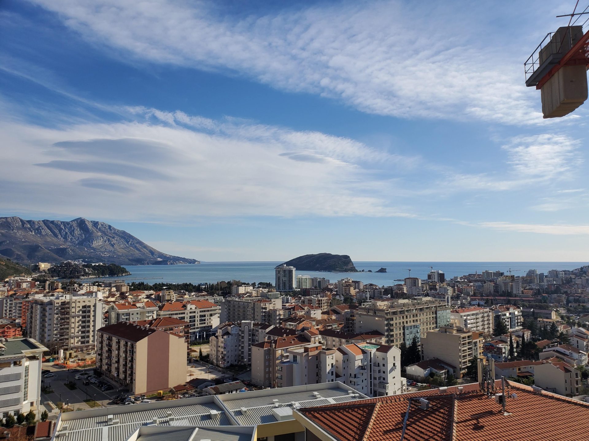 Panoramablick auf die Stadt Budva, das Meer und die Insel Sveti Nikola aus dem Fenster der Wohnung in Montenegro, Blick auf die Berge und die Bebauung.