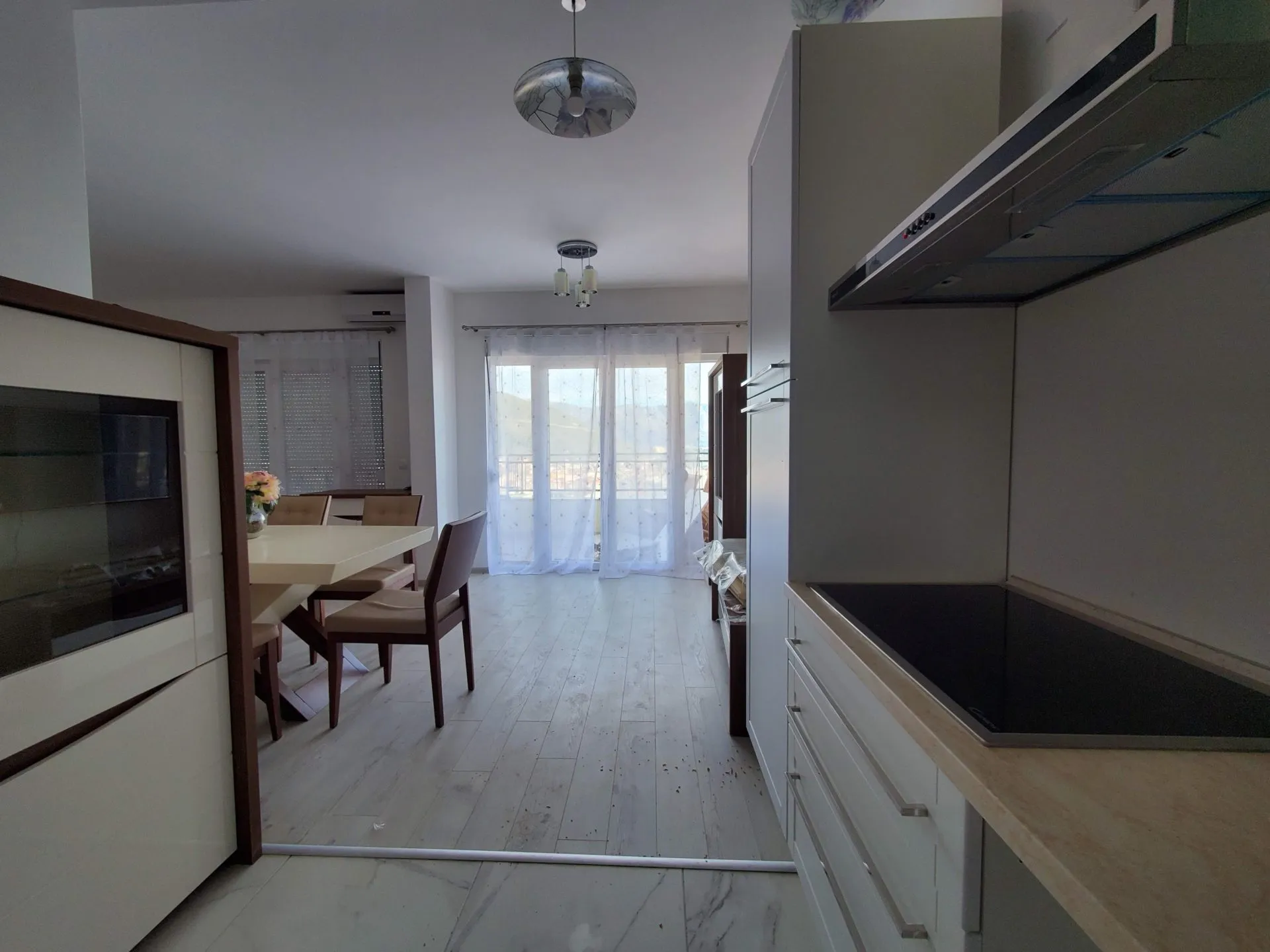 Moderne Wohnküche in einer Wohnung in Budva, Montenegro: helle Möbel, Essbereich und Zugang zum Balkon.