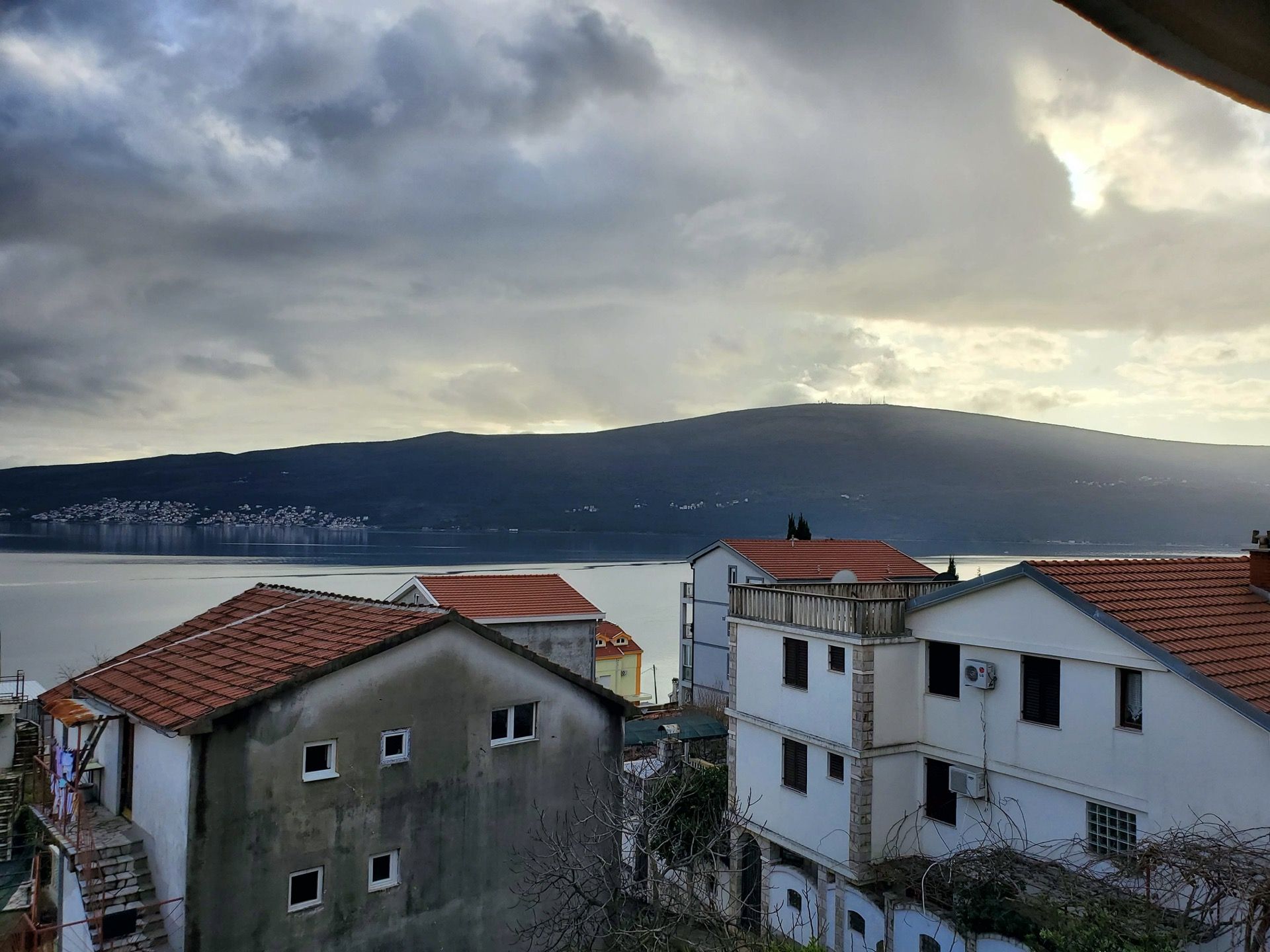 Widok na morze i góry z hotelu w Bijeli, Czarnogóra: panorama wybrzeża z domami mieszkalnymi i dachami z dachówki.