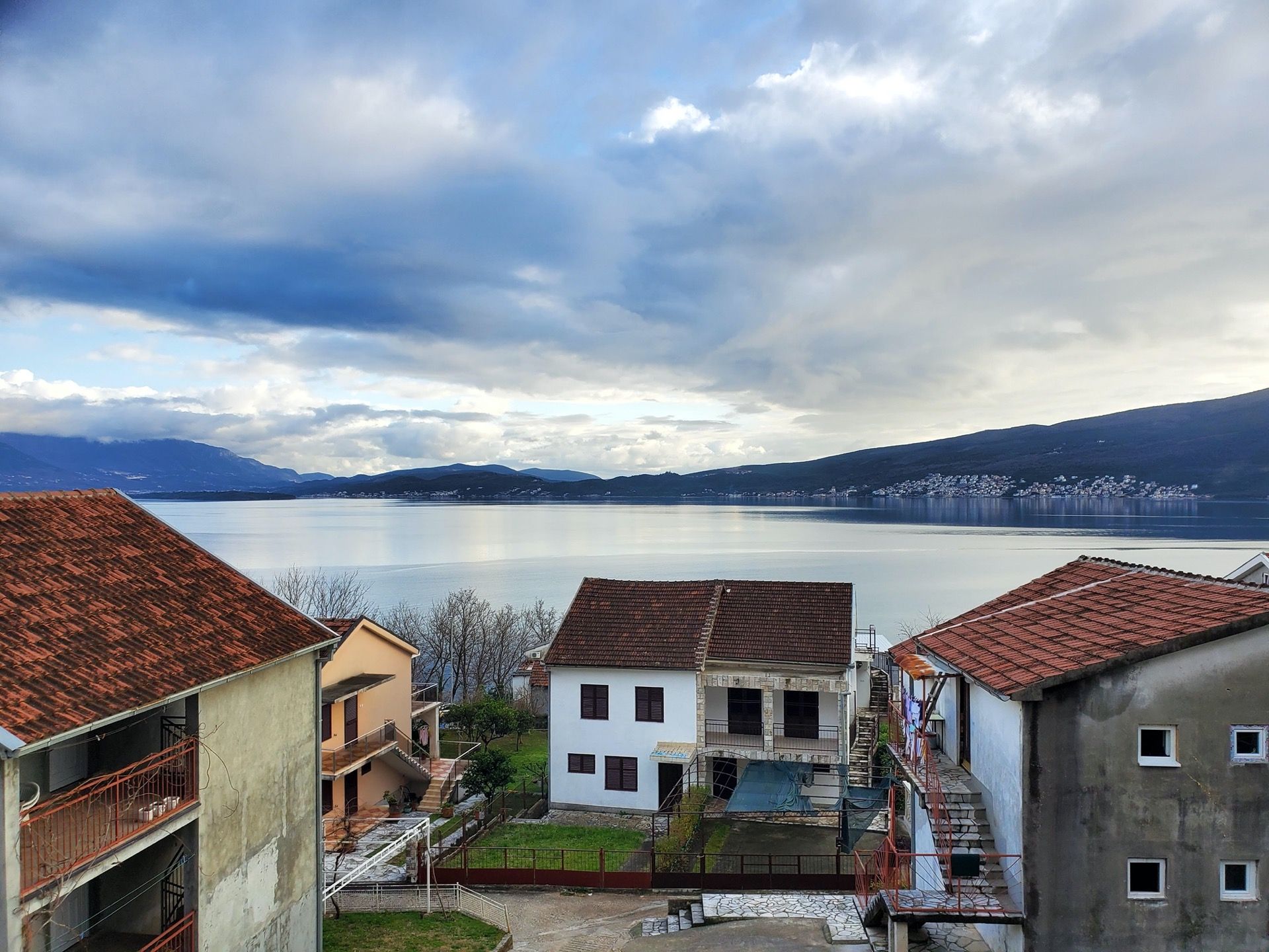 Widok na morze i góry z hotelu w Bijeli, Czarnogóra: prywatne domy z dachami krytymi dachówką i panoramiczny morski krajobraz.